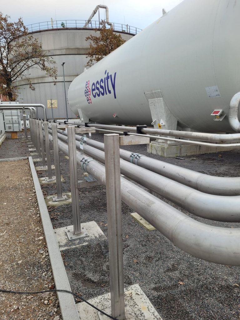 En fältinstallation av ett återförgasningssystem hos kund. Stora rörledning syns bredvid en stor tank.